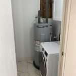 Utility closet with AO Smith water heater and stacked washer and dryer