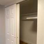 Closet with sliding white door open, showing empty interior and hardwood flooring