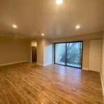 Living room with beige walls, recessed ceiling lights, and sliding glass door