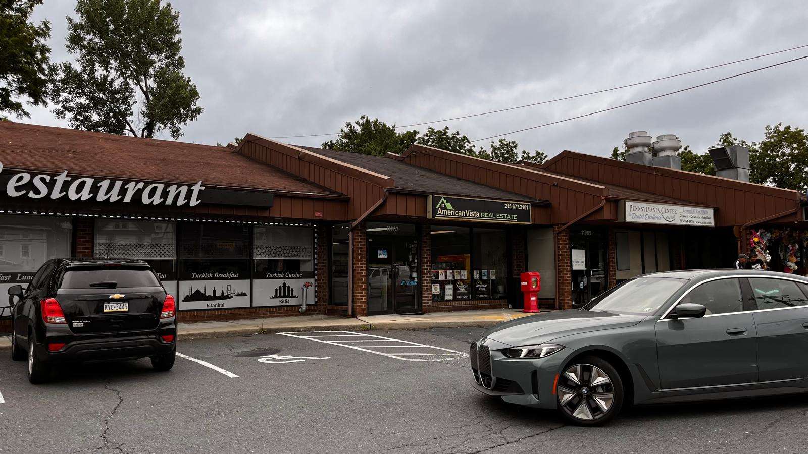 Exterior view of single-story commercial building with parking lot and cars in front